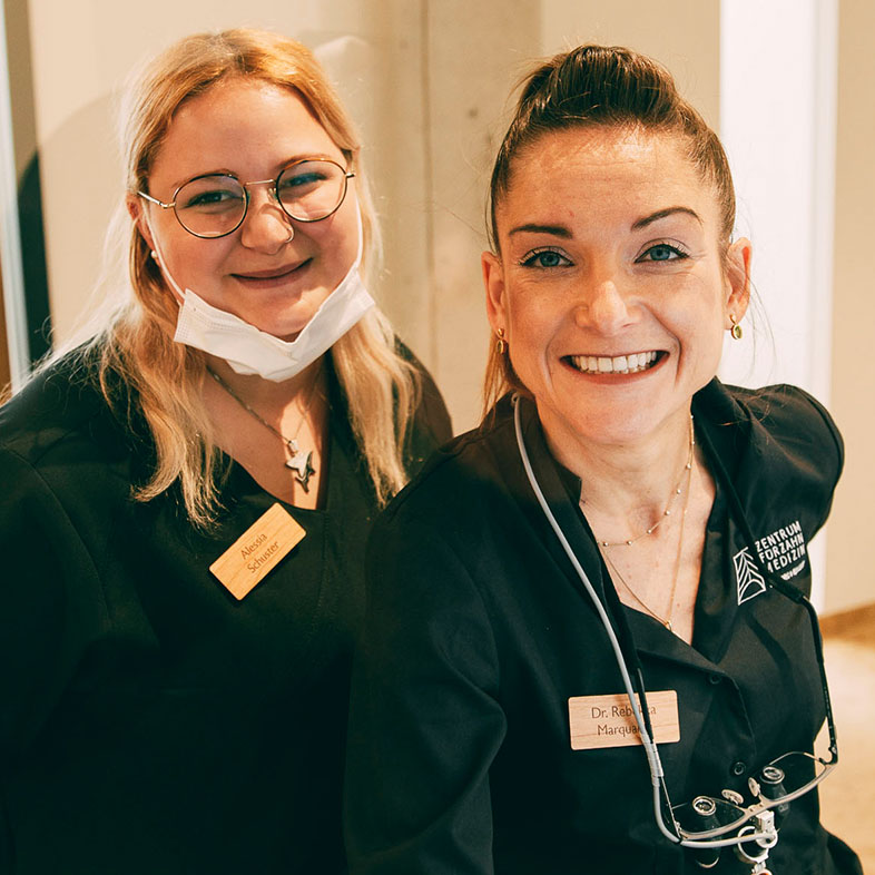 Zwei Mitarbeiterinnen grinsen nach einer erfolgreichen Wurzelbehandlung im Zentrum für Zahnmedizin Dr. Sorg & Kollegen