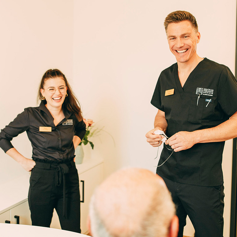 Dr. Sorg und eine Mitarbeiterin lachen mit einem Implantat-Patienten im Zentrum für Zahnmedizin Dr. Sorg & Kollegen